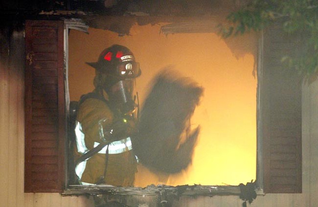 A Central Yavapai firefighter throws some of the burned contents from a house fire in the 4300 block of Katie Circle East in Prescott Valley Thursday night.
