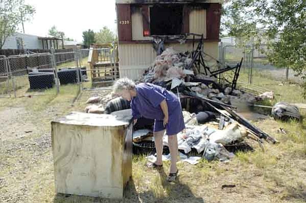 Mary Nagy checks a nightstand Friday afternoon outside her burned residence on Katy Circle East. Nagy and her nephew Dave McClure lost everything in the Thursday evening fire and have no insurance.