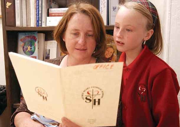 The Daily Courier/Jo.L. Keener 
Janice Barrett and daughter Grace, 8, look over a Sacred Heart School program Friday.  Barrett has two children enrolled in the school.
