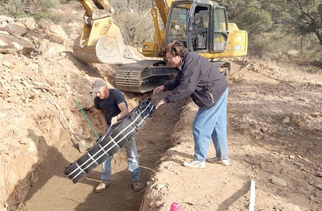 The Daily Courier/Jo.L.Keener
Don Nelson, left takes a filtration section from Lou Brown of Southwest Alternatives as they install an alternative septic system in Crossroads Ranch.