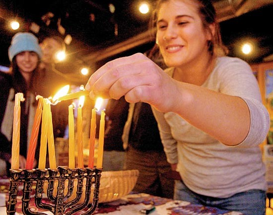 The Daily Courier/Matt Hinshaw
Prescott College student Raizel Liebowitz lights a candle on a menorah during the Hanukkah party at the Prescott College Crossroads Cafe on Tuesday evening.