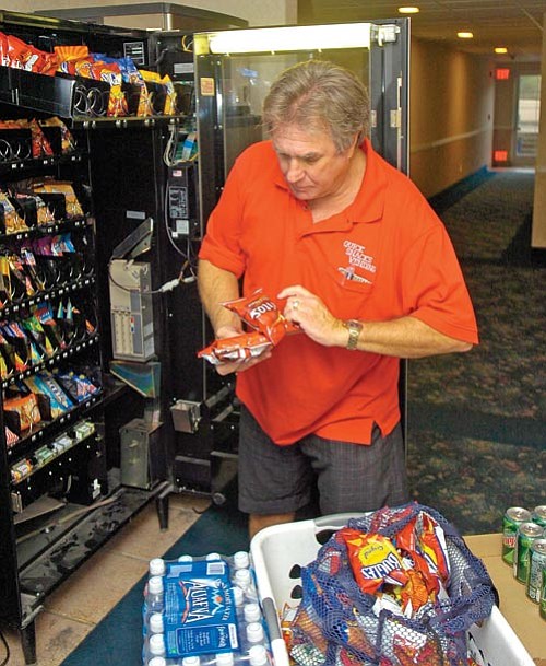 The Daily Courier/Jo. L. Keener <br>
Dan Hersum fills one of his vending machines Monday. Hersum has about 60 machines in the area that are serviced by his company, Quick Snacks.