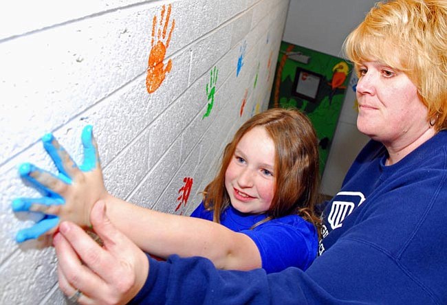 The Daily Courier/Matt Hinshaw<br>
Boys and Girls Club Director of Operations Kelly Byrd helps Emma Lenihan, 10, press her paint-covered hand on a wall inside of the new Prescott Boys and Girls Club on Monday afternoon. There will be a general open house for the new building this Saturday afternoon.
