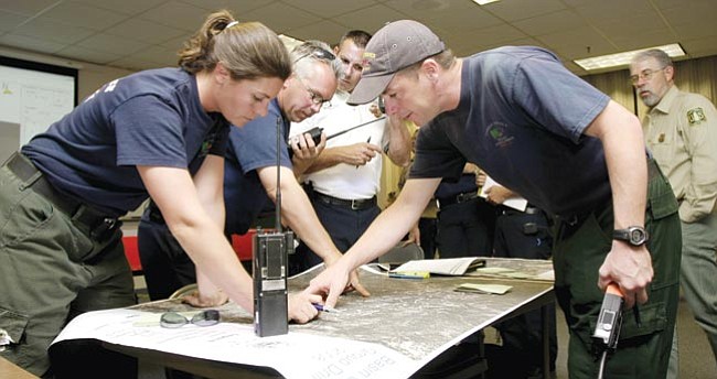 The Daily Courier/Les Stukenberg<br>
Prescott National Forest assistant engine captain Lindsay Yount, left, Prescott Fire Battalion Chief Don Devendorf, Prescott Deputy Fire Chief Ralph Lucas, Prescott National Forest engine captain Aaron Hulburd and Prescott National Forest fire staff officer Mark Johnson look over a topographical map to deploy resources for the 1,200 acre fire they were responding to as part of the annual Basin Drill at the Prescott Fire Center.