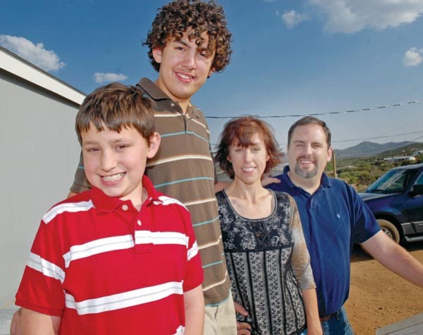 The Daily Courier/Jo. L. Keener<br>
Nicholas Freibott poses on the steps of his Dewey home Thursday afternoon with brother Nathan and parents Melissa and Lenny. All family members have spent time in the Phoenix Ronald McDonald House in support of Nicholas while he was receiving treatment for his leukemia.