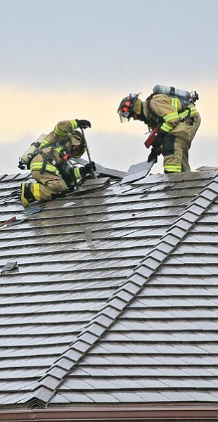 The Daily Courier/Les Stukenberg<br>
Prescott firefighters work to put out a roof fire at a home on Ginseng Way in the Piñon Oaks subdivision that resulted from a lightning strike during the Thursday afternoon storms.

