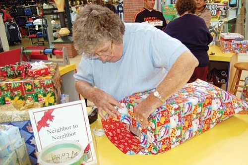 Jerry J. Herrmann/The Daily Courier<p>
Mary Ames, Neighbor 
to Neighbor’s board of directors president, wraps a Christmas present for a customer at Gateway Mall Tuesday.


