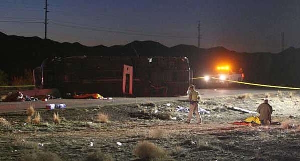 Isaac Brekken/The Associated Press<br>
Officials investigate the scene of a tour bus crash on U.S. 93 near Dolan Springs, Ariz. on Friday night. The Arizona Department of Public Safety says a tour bus overturned on a highway near the Hoover Dam.