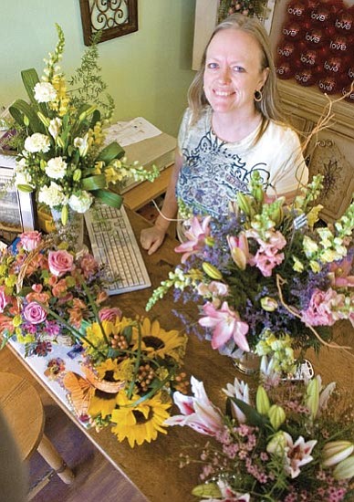 Matt Hinshaw/The Daily Courier<p>
Rakini Chinery, co-owner of Allan’s Flowers, displays a few of the shop’s floral arrangements Wednesday afternoon in Prescott. Jim and Rakini Chinery sold Allan’s Flowers two and a half years ago. The owners they sold to fell on economic hard times and the Chinerys are back behind the counter running the flower shop.