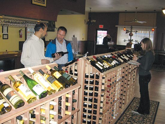 Jason Soifer/The Daily Courier<p>
Jerome Mitchell, left, owner of Jazzy’s Wine Bar & Fine Spirits on north Cortez Street, shows a bottle of wine to Robert Upchurch as Kayla Wilkerson takes inventory.
