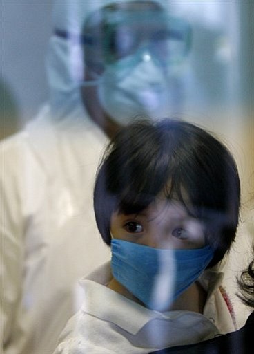 Eduardo Verdugo/The Associated Press<br>
Wearing a face mask as a precaution against swine flu, a child, in his mother's arms, is seen through a glass door leaving the emergency area where people with swine flu-like symptoms are checked at the Naval hospital in Mexico City, Wednesday. Arizona's first confirmed case of the new swine flu virus is from Maricopa County.