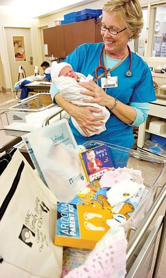 Matt Hinshaw/The Daily Courier<p>
Yavapai Regional Medical Center Registered Nurse Heidi Alessi cradles a newborn baby girl in her arms next to the YRMC's new mom gift bag and its contents Friday afternoon at YRMC in Prescott. 


