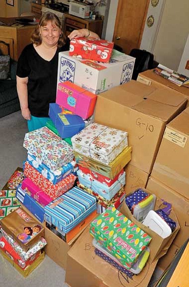 Matt Hinshaw/The Daily Courier<br>
Ruthie Claybaugh stands next to a portion of her donations for Operation Christmas Child at her home in Prescott. Claybaugh spends all year collecting toys, clothing and school supplies and packing them in shoeboxes to donate to Samaritan's Purse.