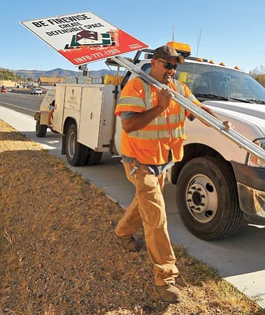 Matt Hinshaw/The Daily Courier<p>
City of Prescott traffic control employee Roy Madris carries one of the new Firewise signs to the intersection of Iron Springs Road and Williamson Valley Road Thursday afternoon.

