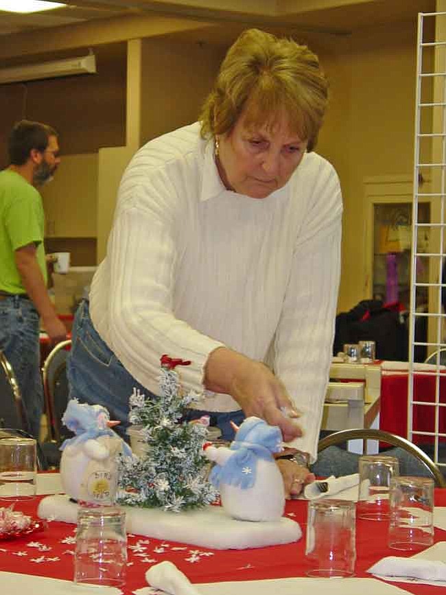 Barbara Jensen sprinkles confetti snowflakes on decorated tables for the 29th annual "Don't Spend Christmas Alone Dinner" at St. Luke's Episcopal Church. This year's event is already in the planning stages. (Courier file photo)
