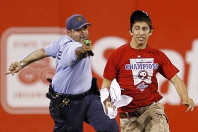 Matt Slocum/The Associated Press<br>On Monday, a law enforcement officer chases down Steve Consalvi, who ran on to the field before the eighth inning of a game between the Phillies and Cardinals in Philadelphia. The officer used a Taser gun to apprehend Consalvi.