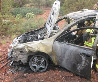 Yavapai County Sheriff’s Office/Courtesy<br>
Firefighters examine the interior of a car that burst into flames after being hit by a white SUV – likely a Dodge Durango – with a partial Arizona license plate number of 7VT.