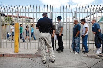 Jae C. Hong/The Associated Press<br>A group of illegal immigrants look at pedestrians as they are processed for deportation at the Nogales Port of Entry in Nogales, Az., Wednesday. A federal judge on Wednesday blocked the most controversial parts of Arizona's immigration law from taking effect, delivering a last-minute victory to opponents of the crackdown. The overall law will still take effect Thursday, but without the provisions that angered opponents — including sections that required officers to check a person's immigration status while enforcing other laws.


