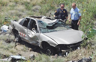 Les Stukenberg/The Daily Courier<br>Prescott Police officers Nathan Barto and Clayton Heath look over the wreckage of a car that flew through the median and over the guardrail off of Prescott Lakes Parkway about 1/2 mile east of Highway 89 on Wednesday afternoon. The single occupant was ejected and killed in the accident.