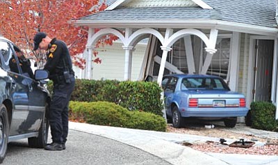 Les Stukenberg/The Daily Courier<br>
Prescott Valley Police Corporal Mike Morris fills out a report on a man who was arrested after running his car over a Morris' foot and into this Victorian Estate home while fleeing from a traffic stop on Highway 69 near Sundog Ranch Road  Friday evening.
