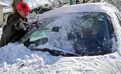 Matt Hinshaw/The Daily Courier<br>John McCormick cleans off his winshield after digging his car out of the snow Thursday morning in Prescott.