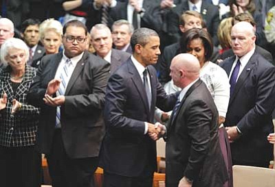 J. Scott Applewhite/The Associated Press<br>President Barack Obama shakes hands with Mark Kelly, the husband of Rep. Gabrielle Giffords, as first lady Michelle Obama watches at a memorial service in Tucson for the victims of a shooting rampage that that killed six people and left 14 injured, including Giffords, on the University of Arizona campus, Wednesday. Daniel Hernandez, a University of Arizona political science student who helped Giffords when she was shot, applauds at left. 
