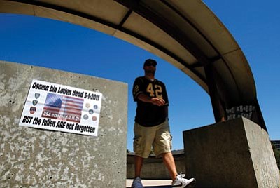 Ross D. Franklin/The Associated Press<br>
A visitor wearing an Arizona State University Pat Tillman football jersey, exits the Arizona 9/11 Memorial, passing a makeshift sign attached to the memorial about the death of Osama bin Laden on Monday.