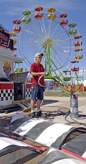 The Daily Courier/File<br /><br /><!-- 1upcrlf2 -->Jerry Calloway of Casa Grande cleans his booth's awnings as a ferris wheel looms at rear at a previous Prescott Valley Days event.