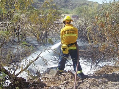 Courtesy photo<br>
A Black Canyon Fire Department firefighter sprays water on a wildfire that someone started Wednesday with a cutting torch.
