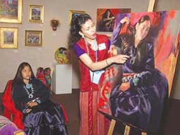 Courtesy photo<br>Gretchen Lopez points out details in one of her colorful paintings.