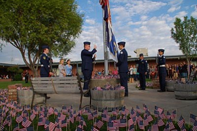 Lisa Irish/The Daily Courier<br>
Eddie Golsen, left, and James Lovell raise the flags Monday outside Prescott High in front of students and teachers gathered for the 9/11 Remembrance.