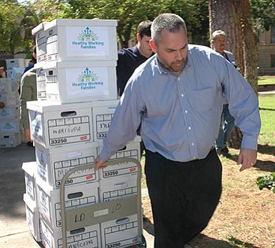 State Elections Director Eric Spencer hauls boxes of petitions submitted Thursday. (HOWARD FISCHER/Capitol Media Services)