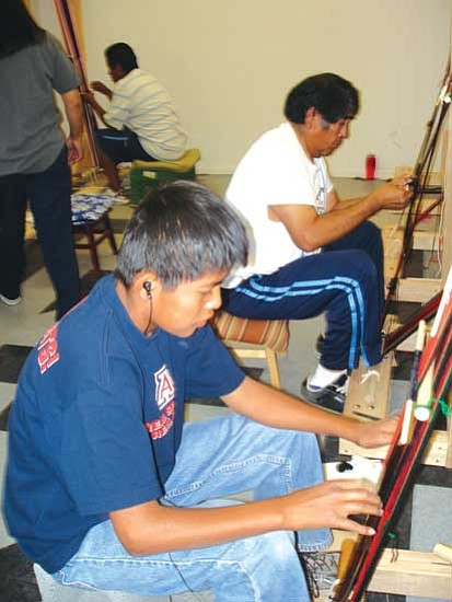 <i>Photo by Rosanda Suetopka Thayer/NHO</i><br>
A couple of students work on traditional weavings in master weaver Marvin Pooyouma's Hopi belt-weaving weaving class, which is a part of the Hopitutuquiki art school. Each student learned&#160;how to set up a&#160;traditional loom, design and finish an entire Hopi&#160;men's traditional red-black-green belt within their two week session. Pooyouma is from the village of Hotevilla.