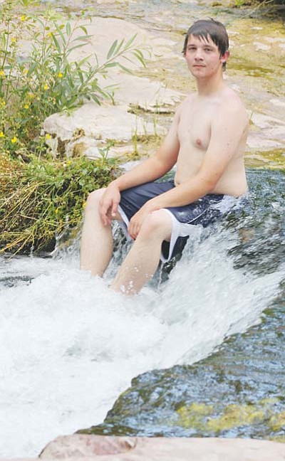 <i>Stan Bindell/NHO</i><br>Brandon Johnson enjoys the cool cascade of a small waterfall while sitting near wildflowers.
