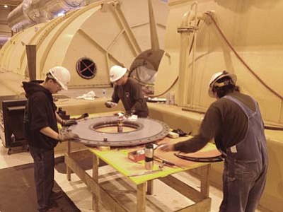 Photo/George Hardeen<br>
From left to right, Mitchell Emerson, Myron Whitehorse and Durral Whitehorse clean a section of the “T-8” bearing oil deflector by hand. This is a critical part of the Navajo Generating Station Unit 3 turbine behind them. They are among some 800 skilled workers involved in this year’s four-week-long, $16 million annual minor overhaul. 
