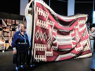 Volunteers attempt to hold up Bessie Yazzie’s 12-foot-9–inch by 9-foot-9-inch rug in preparation for the auction.