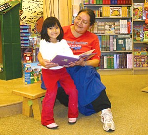 Jaelyn Dechilly, age 4, beams proudly as her mother Dianna reads to her. Jaelyn is a student at Codgill Head Start, which is one of 26  Northern Arizona Council of Governments (NACOG) Head Start Centers here in Flagstaff. NACOG recently received a donation of 130 children’s books to distribute to all of their Head Start centers Photo by Rebecca Schubert/Observer).