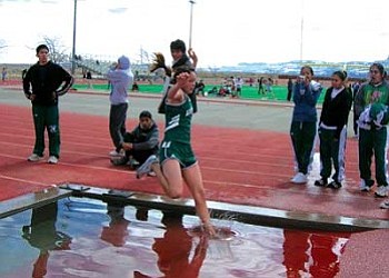 Sophomore Tiffany Nez leaps through the water pit on her way to victory in the 2,000-meter steeplechase. Nez later scored in the 800-meter run and ran a leg on Tuba City’s victorious 4x400-meter relay (Photo by Carl Perry/TCHS).