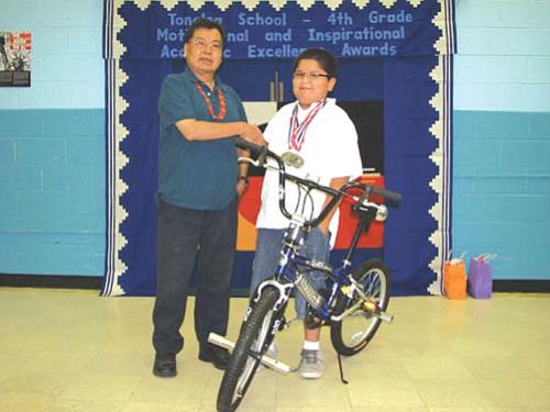 Mykelti Curley stands with Mr. Blake next to his new awarded bike received for perfect attendance all school year.