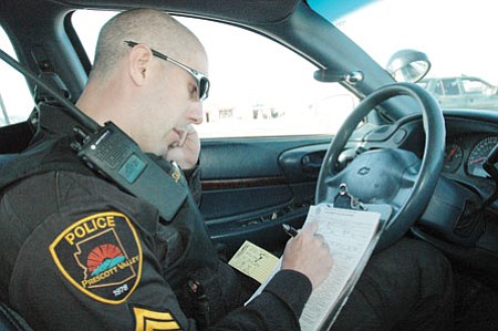 Prescott Valley Police Sgt. Kel Palguta writes a ticket for a driver during Friday's speed detail on Highway 69 near Sundog Ranch Road. Fifteen officers on motorcycles and in patrol cars stopped drivers who were travelling more than 10 mph over the speed limit at the entrance to Prescott Valley, where four crashes have occurred already this year..They gave out 92 citations for various violations including speed during the three and half hour patrol.<br>
TribPhoto/Heidi Dahms Foster