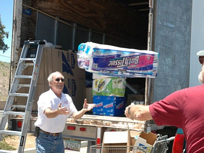 Ernie Johnson, a Master’s Touch driver, tosses a case of bath tissue to Jerry Schultz as volunteers loaded an 18-wheeler with supplies for victims of tornadoes in Joplin, Missouri. The truck and volunteers left Prescott Valley on Sunday.<br>
TribPhoto/Cheryl Hartz