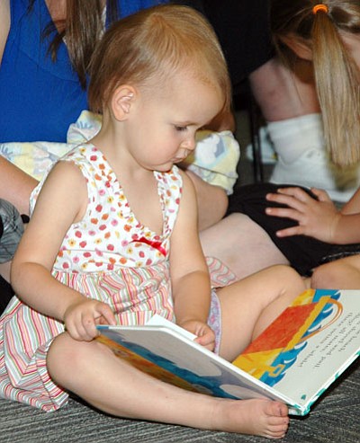 Klella Maestri, 2, is into a picture book while around her, children watch a  Storytime presentation on yo-yos at the Prescott Valley Public Library June 10.<br>
Trib Photo/Cheryl Hartz