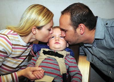 Holly and Royce Stringer kiss their 19-month-old son Brennan, who has Tay-Sachs disease, a rare disorder that progressively destroys nerve cells in the brain and spinal cord.<br>
Photo courtesy Les Stukenberg/The Daily Courier