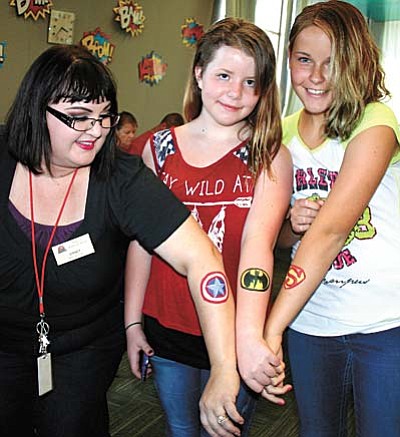 Trib Photo/Sue Tone<br /><br /><!-- 1upcrlf2 -->Showing off their favorite super hero logos at the Teen Summer Reading Program Launch Party June 1 are, from left, Teen Librarian Ginney Bilbray, Valli Hall-Moran and Amanda Lantz.