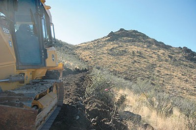 A worker carefully begins grading the first in a serious of gentle switchbacks that lead to the summit of Glassford Hill. Once completed, the new trail will allow pedestrians and bicyclists a scenic way to traverse the historical hill. (Briana Lonas)