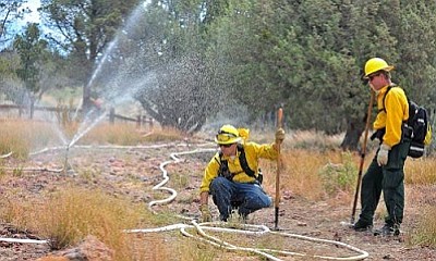 Matt Hinshaw/The Daily Courier<br>
Verde Valley Fire Department Firefighters Bruce Hagberg and Paul Morales check the lines on a defensive sprinkler system just behind a home in Sundown Acres near the Doce Fire Friday morning west of Prescott.