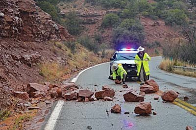 Highway Patrol Officers lift boulders off SR Route 89a in Oak Creek Canyon Monday after they slid off a cliff one mile north of Sedona in the rain. VVN/ Vyto Starinskas