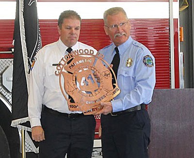 Retiring Engineer-Firefighter Larry Wright holds metal art plaque commemorating his service. (Courtesy Cottonwood Fire)
