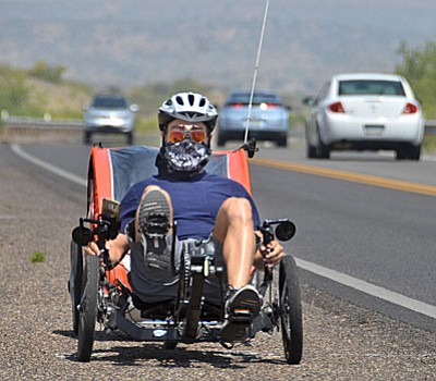 Alex Zanfif of Toronto, Canada, rides with a bandana on his face to protect himself from smoke between Cottonwood and Camp Verde on SR260 on Tuesday morning. Zanfif said he is riding from Ventura, Cal., to Phoenix. He used the bandana in the Mojavi Desert for dust and had to take it out again Tuesday when he woke up to a considerable amount of smoke in the air The smoke is caused by nearby wildfires. VVN/Vyto Starinskas