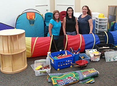 From left, Shara Coughlin (Preschool Aide), Cindy Cunningham (Associate Pastor) and Sonia Feldtkeller (Preschool Director) kneel among some of the items being donated by the VOC Nazarene Church to Big Park Community School’s new Sedona Integrated Preschool, a school that blends conventional and special education students.<br /><br /><!-- 1upcrlf2 -->